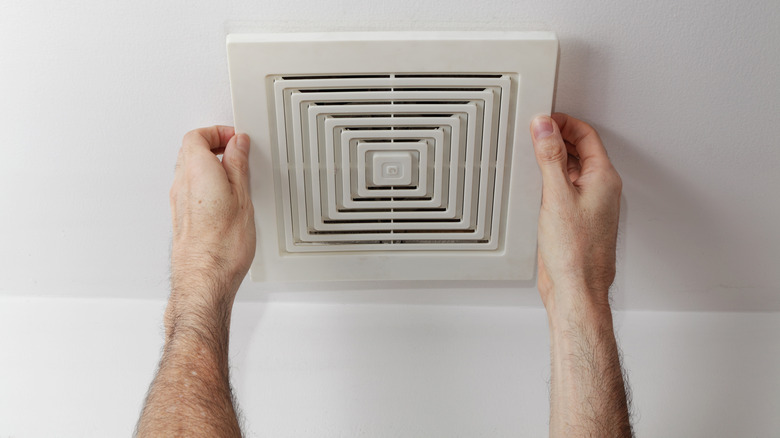 Hands grabbing ceiling vent cover
