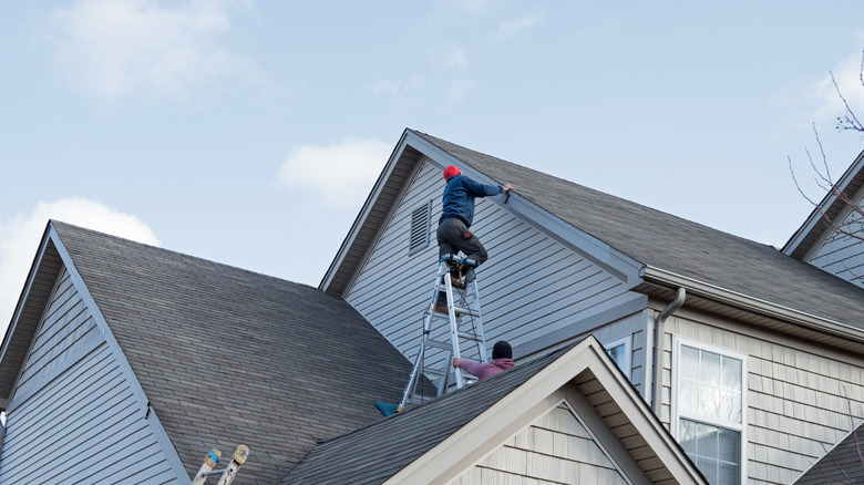 Roofers repairing trim along a roofline