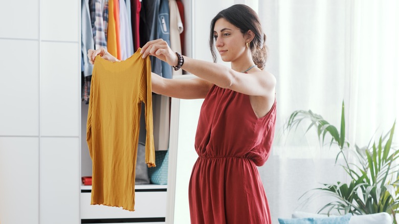 Woman holding an orange t-shirt in her room