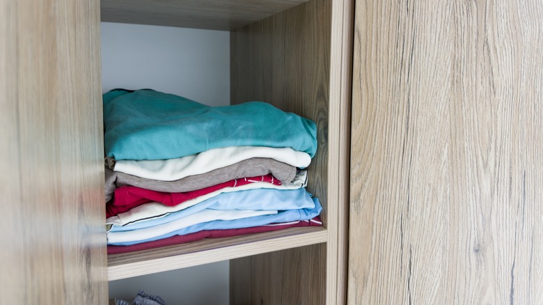 Colorful t-shirts folded and stacked in a closet shelf