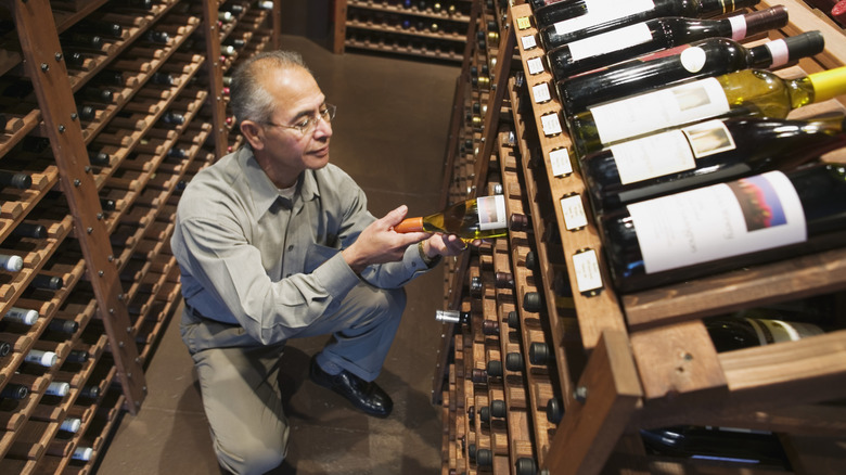 Man examining bottle of wine in a cellar