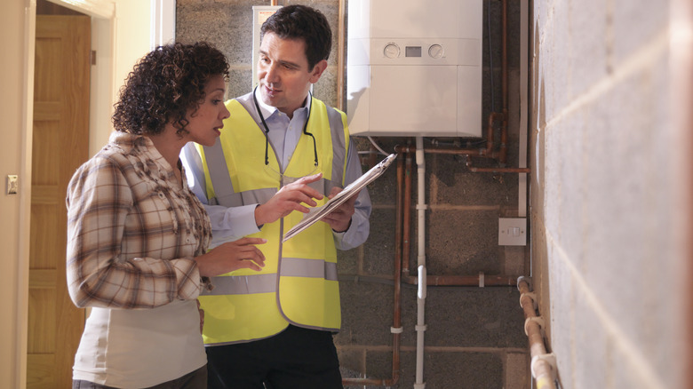 A contractor with a notepad talking to a woman in a basement