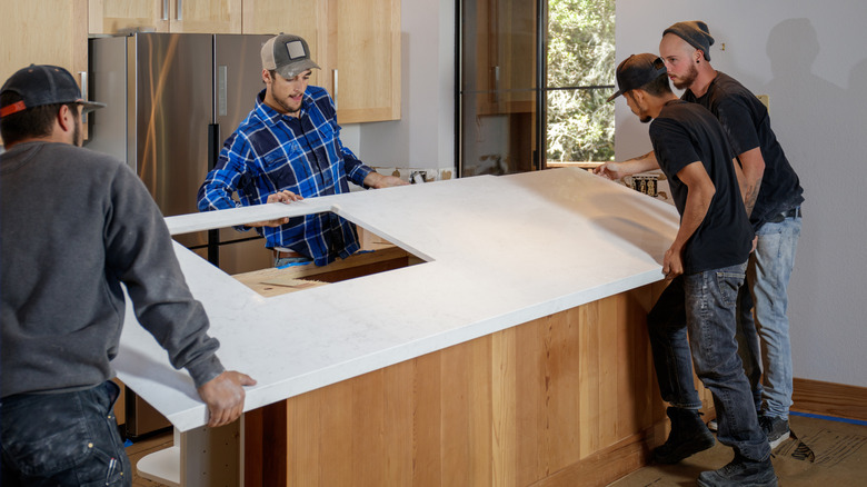 People installing countertop in kitchen