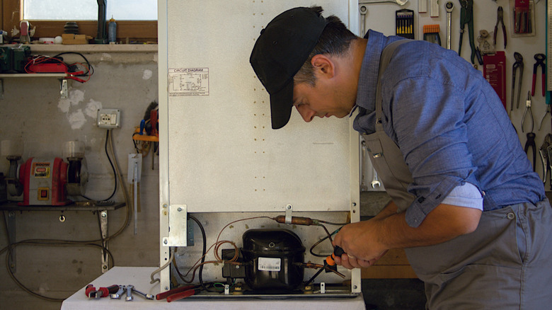 a repairman working on a freezer in a garage