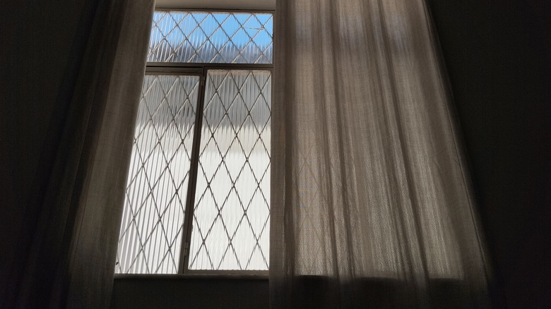 Close-up of a window with a half-drawn curtain