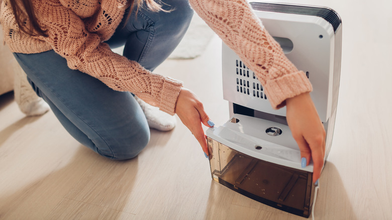 Woman pulling out water tank on dehumidifier