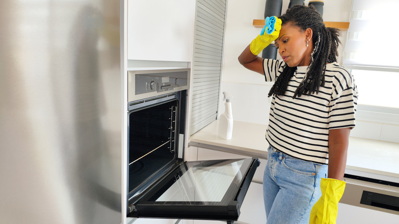 Woman tired cleaning an oven