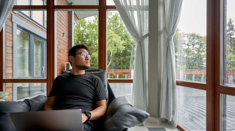 Korean man looking at the storm through a window