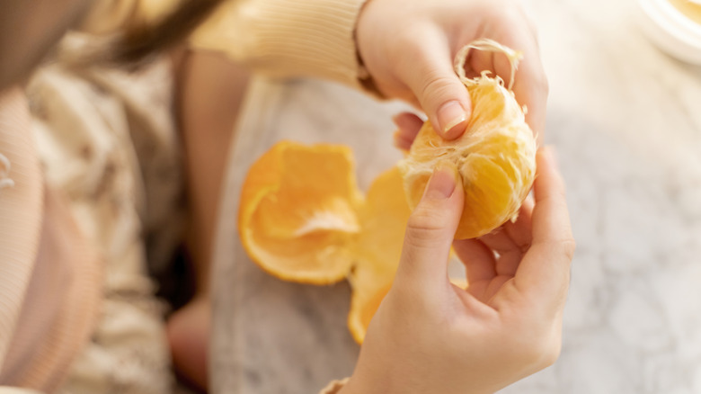 A woman's hands peeling an orange