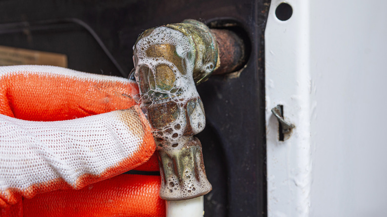Inflating bubbles of soap on the pipe of a kitchen gas stove