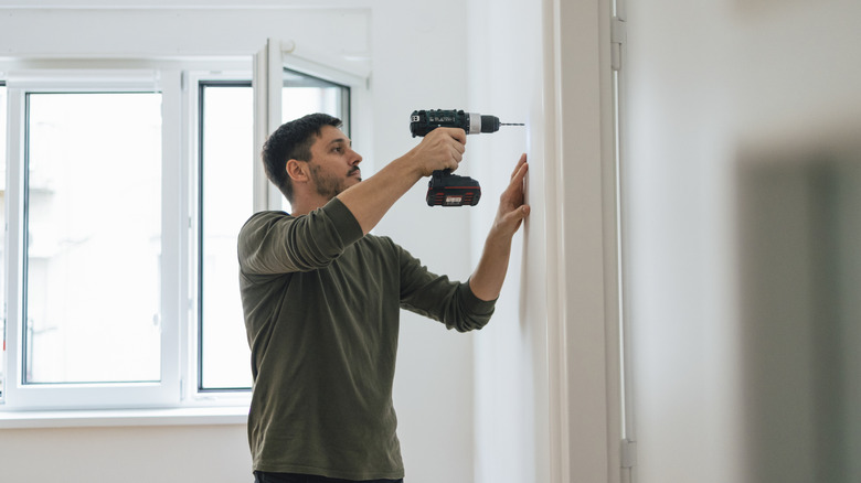 Man using drill on wall in home