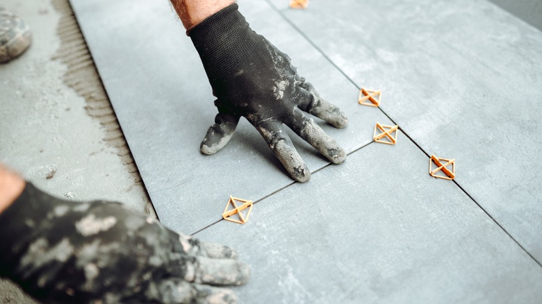 Person laying tiles with spacers and grout