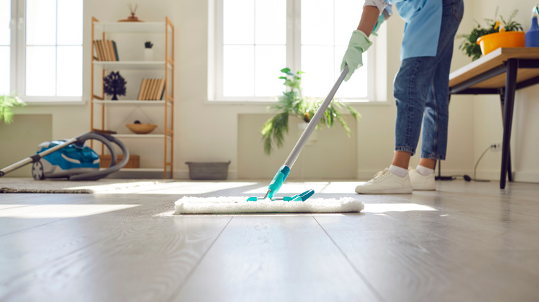 Person with rubber gloves using microfiber mop on a laminate floor