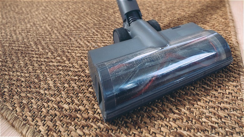 Vacuum head cleaning a dirty jute rug.