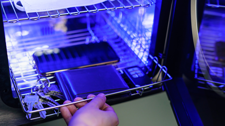 Phone, wallet, and keys being placed inside a UV light sanitization box
