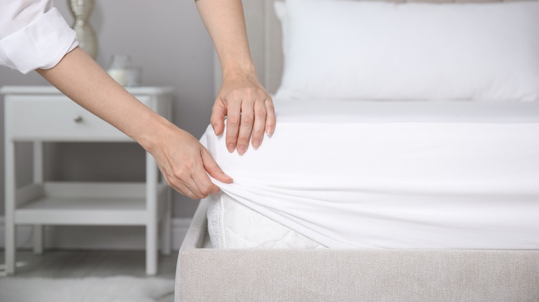 person fitting white bedsheets