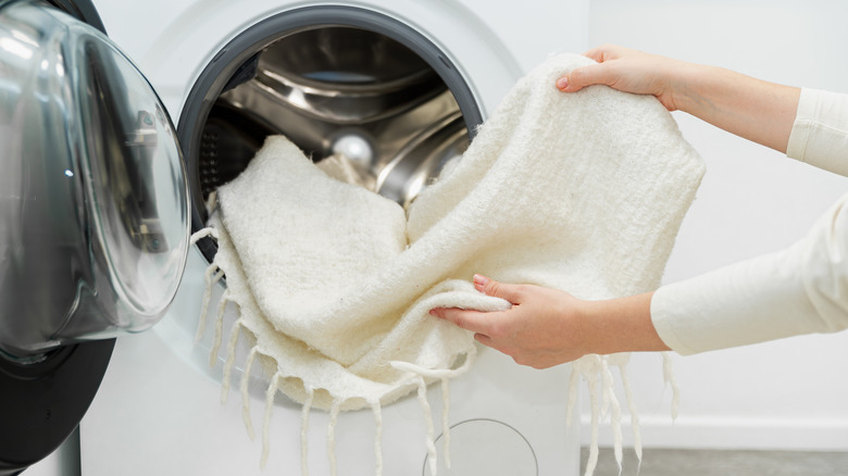 woman's hands pulling throw blanket out of dryer