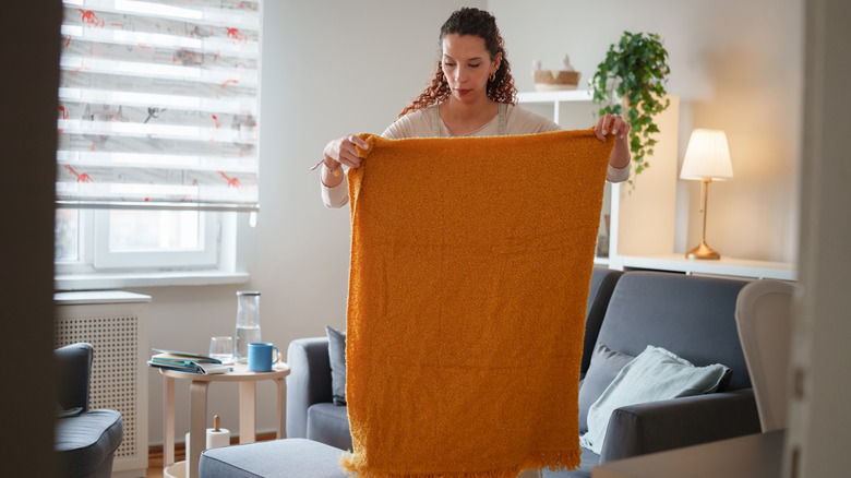 Woman folding a blanket in her living room