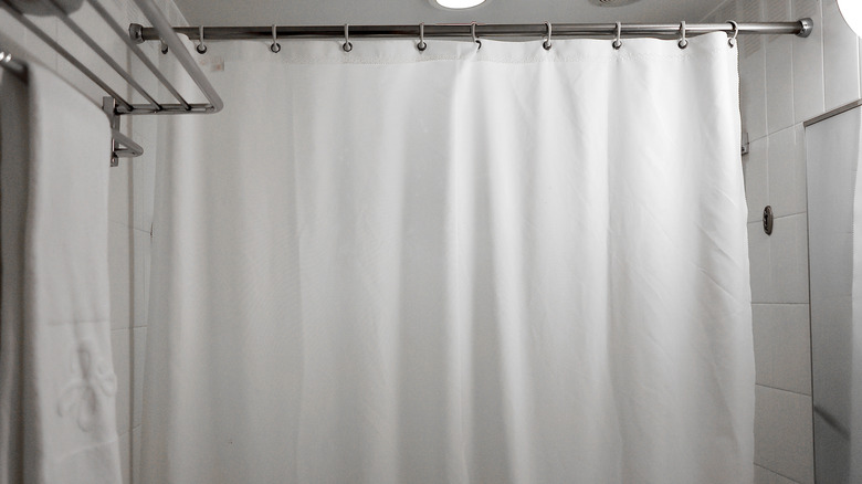 A clean, modern bathroom with a white shower curtain liner handing.