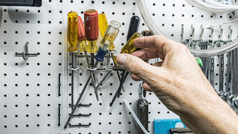 person grabbing a screwdriver for repairs