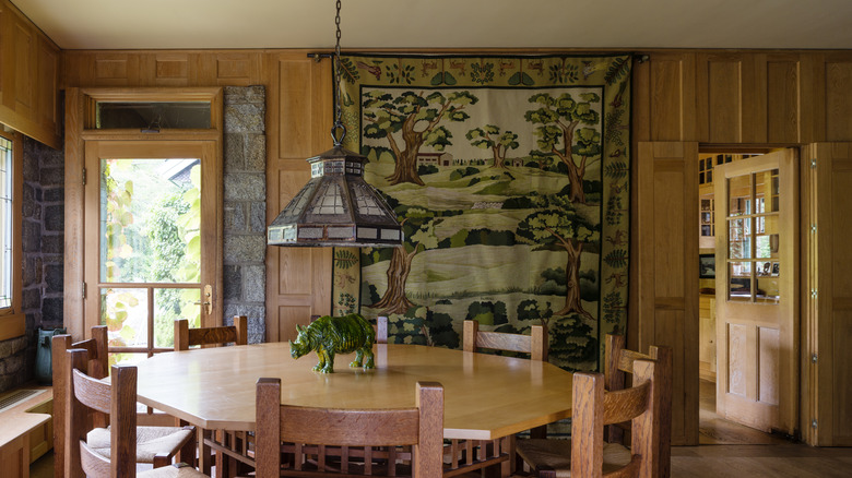 A large tapestry hangs from near the ceiling to the floor in a dining room