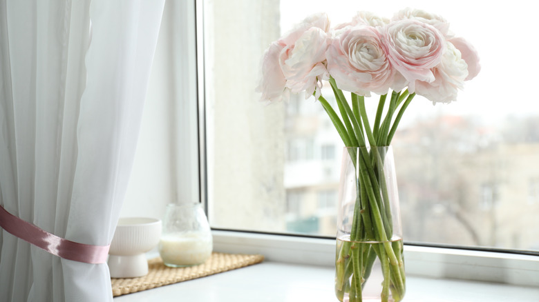 Glass vase with roses on a windowsill