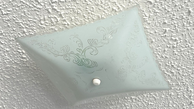 A closeup of a light fixture and a popcorn ceiling