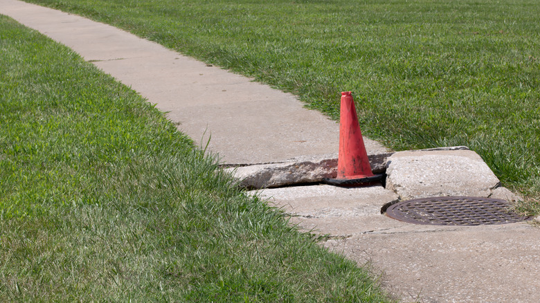 Broken sidewalk with an orange warning cone