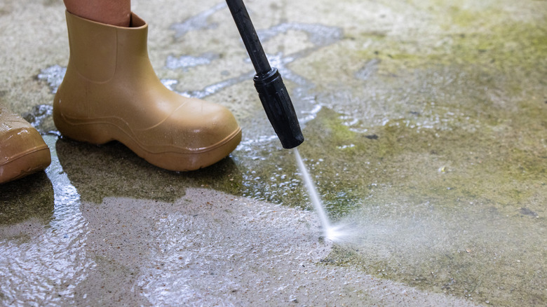 Person cleaning a sidewalk with a power washer