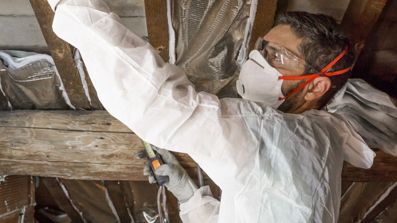 man with protective gear and white smock in attic