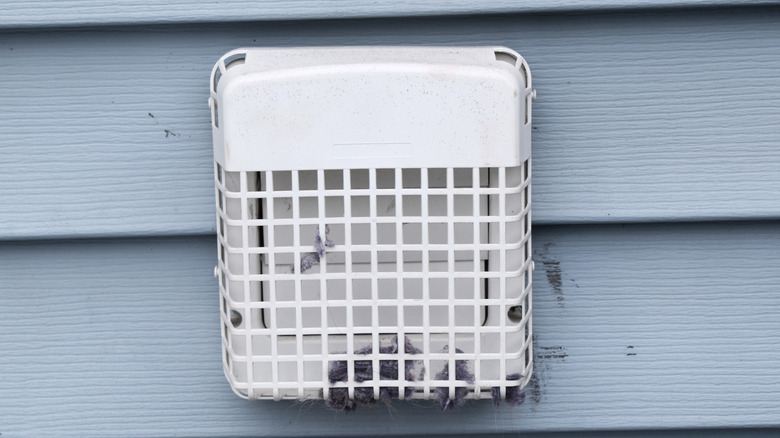 An outdoor vent shows discolored marks on nearby siding