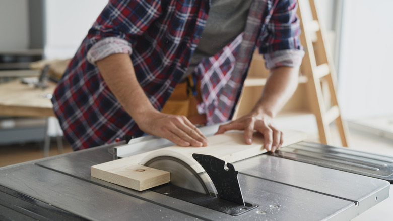 person cutting wood with table saw