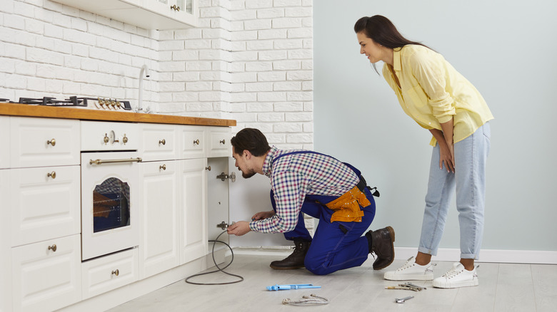 Plumber clearing a sink drain while a homeowner watches