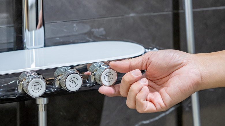 Close up of person adjusting high tech shower faucet with adjustable temperature options
