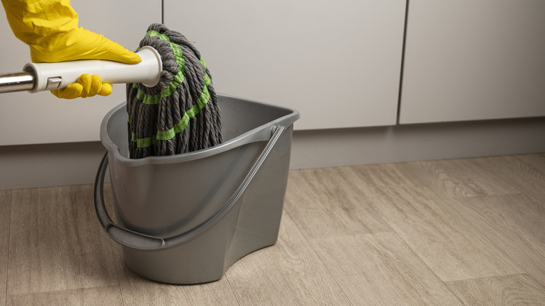 Hand wringing out mop in bucket