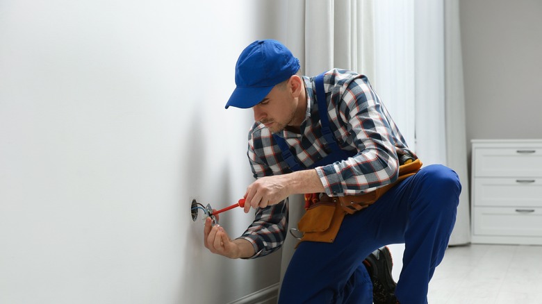 Electrician repairing outlet in home