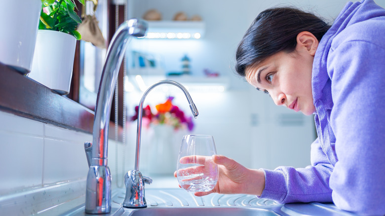 Woman looks at leaking faucet