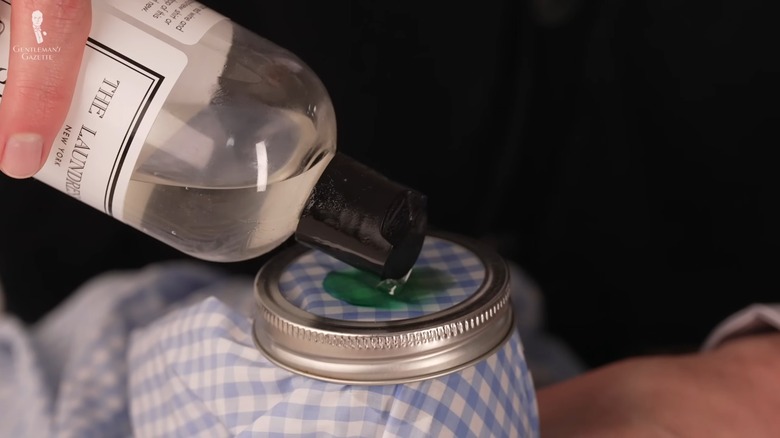 Hand pouring liquid soap on a green ink stain