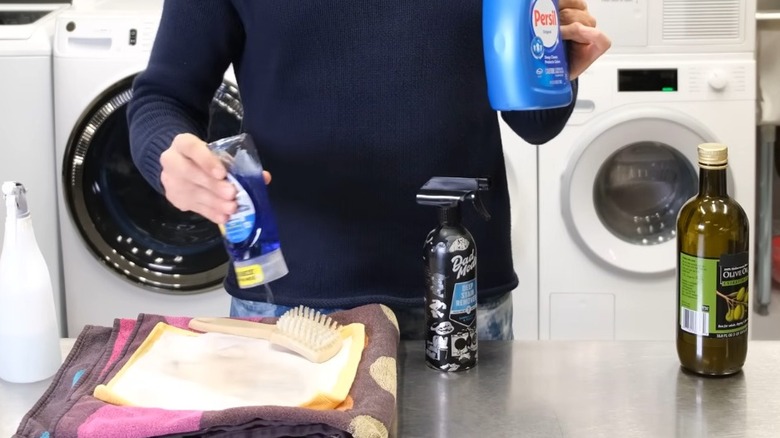 Man adding a few drops of dish soap on oily stains