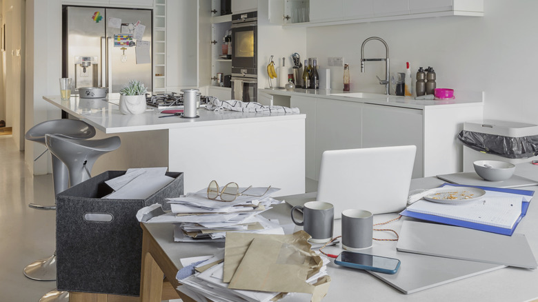 A cluttered kitchen countertop and table