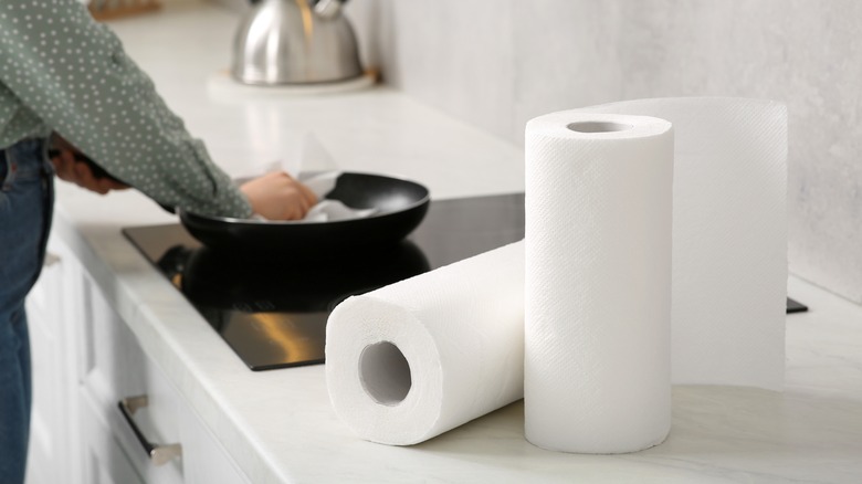 Person's hands cleaning a pan with a paper towel