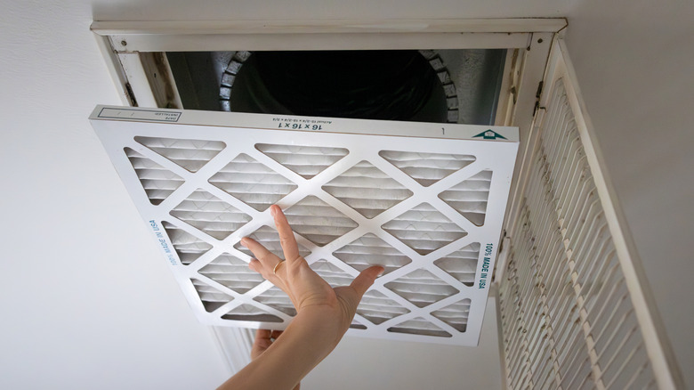 Person placing filter into ceiling vent