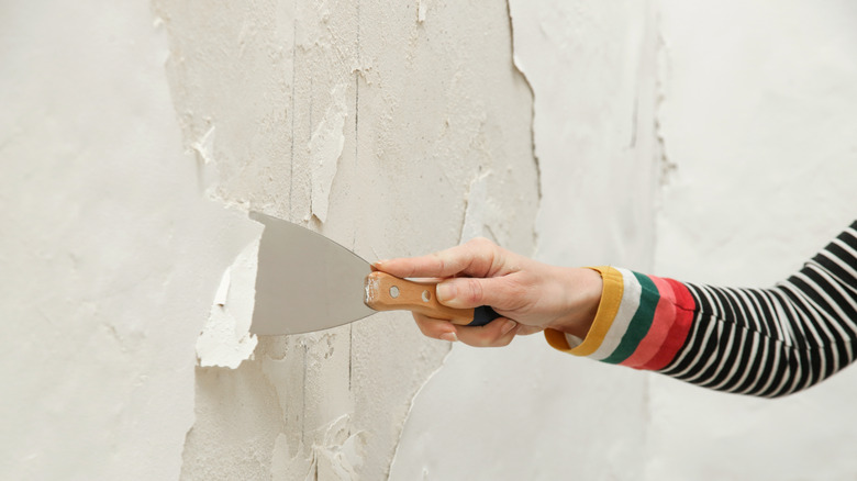 Person scraping paint off a wall