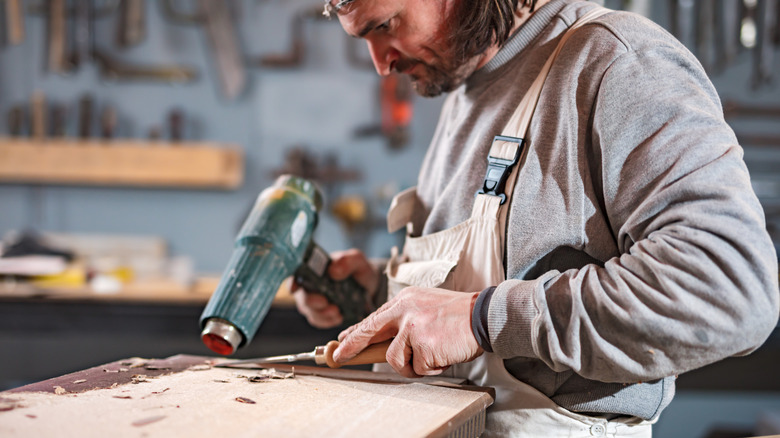 Man removing paint with a heat gun