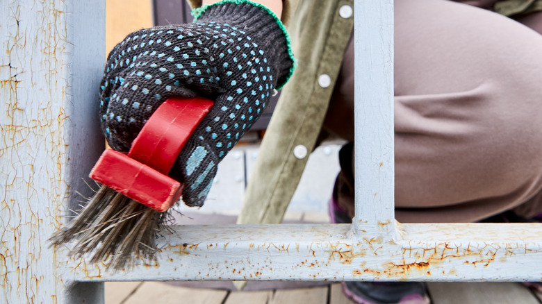Person using brush to scrape paint