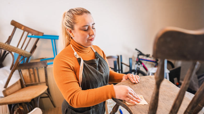 A woman sanding an antique chair for painting