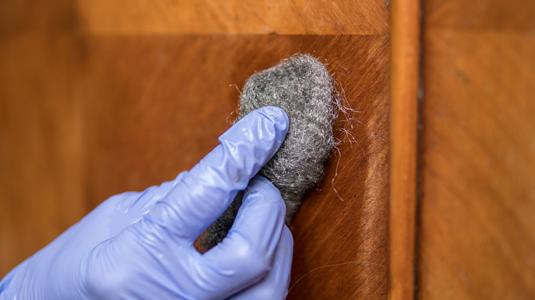 Person restoring wood surface with steel wool