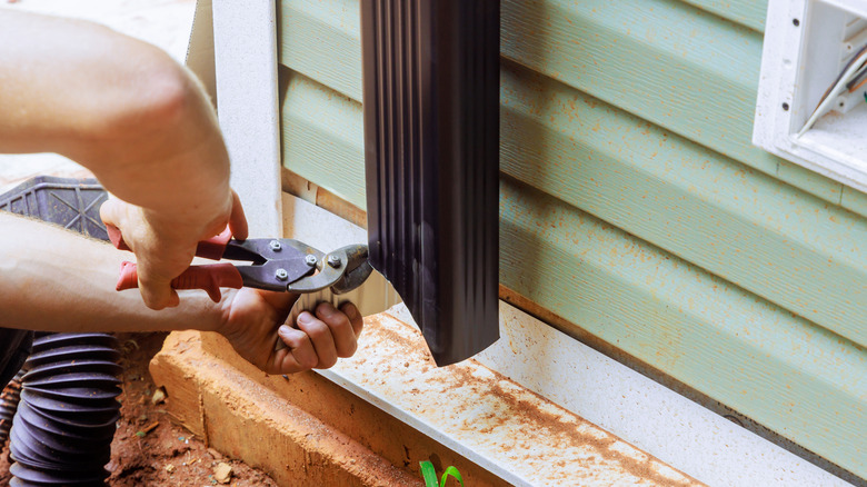 Close up of handyman adjusting gutter downspout