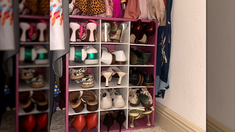 Painted pink and white shoe rack filled with high heels and sandals inside a closet