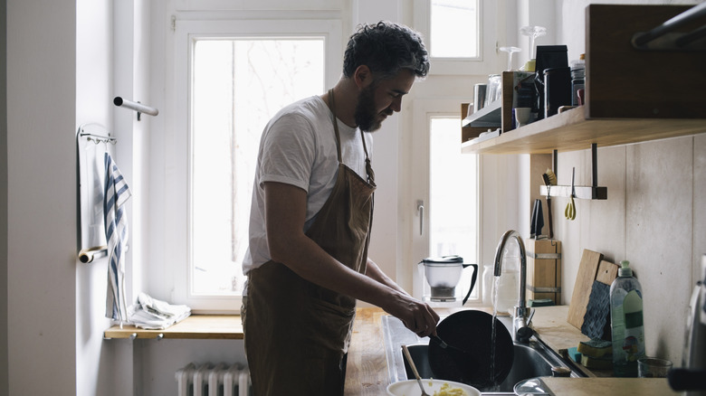 Man washing dishes in a kitchen